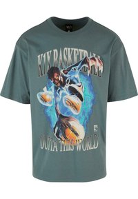 Tyrkysové tričko s krátkým rukávem se š grafickým potiskem basketbalisty v pohybu. Text zní: „K1X BASKETBALL OUTTA THIS WORLD.“