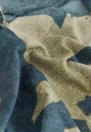Katoenen stof met een gestructureerd oppervlak, voorzien van een blauw camouflagepatroon op een neutrale achtergrond. Subtiele variaties in kleurdichtheid.