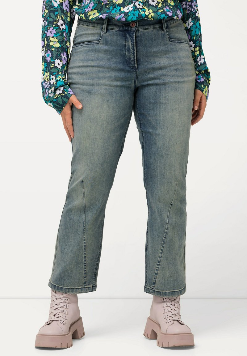 Vaaleansiniset farkut, joissa on suora lahje, keskikorkea vyötärö ja etutaskut, yhdistettynä vaaleanpunaisiin nauhaketjuihin.