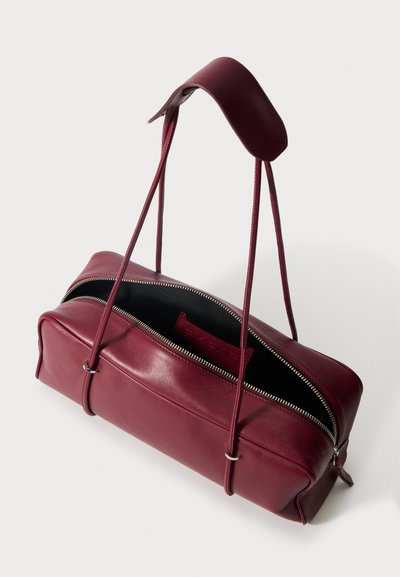 Burgundy nahkalaukku, jossa on kaksi pitkää hihnaa, suorakaiteen muotoinen, sileä pinta, ylhäältä avautuva vetoketjusulku ja musta sisustus.