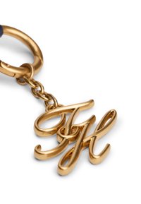 Porte-clés en métal doré avec des lettres entrelacées "G" et "H", finition lisse et brillante, et anneau de fixation solide.