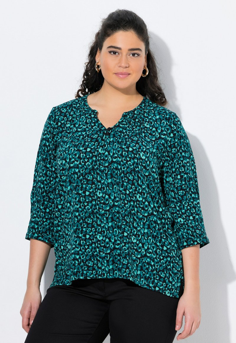 Blusa turchese con motivo leopardato, maniche a 3/4, scollatura a V e pieghe sottili sul davanti. Realizzata in tessuto leggero e strutturato.