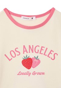 T-shirt crema con collo rosa. Presenta una stampa grafica con "LOS ANGELES", due fragole e "Locally Grown" in lettere rosa.