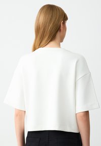Witte cropped t-shirt met korte mouwen, gemaakt van gladde stof. Heeft een ronde halslijn en een eenvoudig, minimalistisch ontwerp.