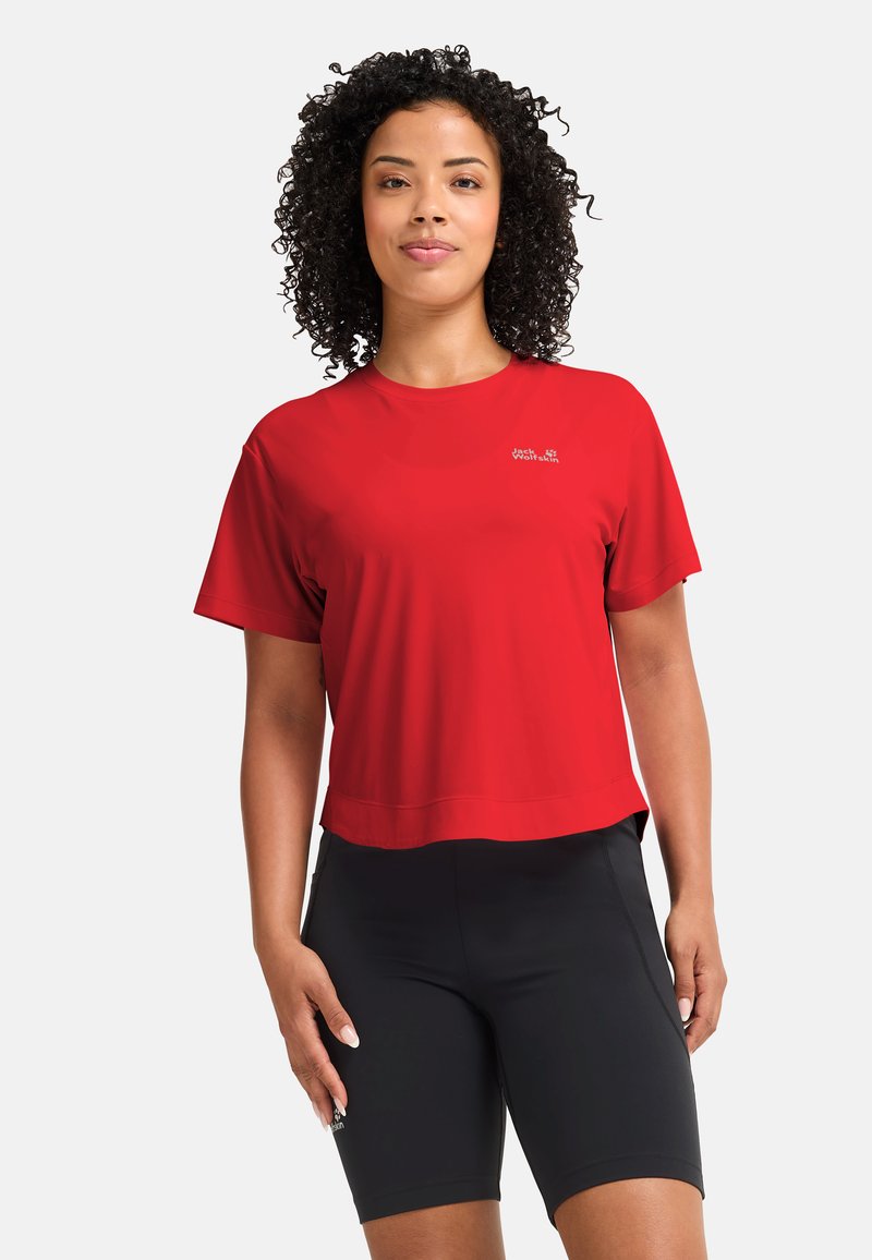 Haut de sport rouge à manches courtes en tissu lisse, avec un col rond et un logo sur la poitrine, assorti à un short de compression noir.