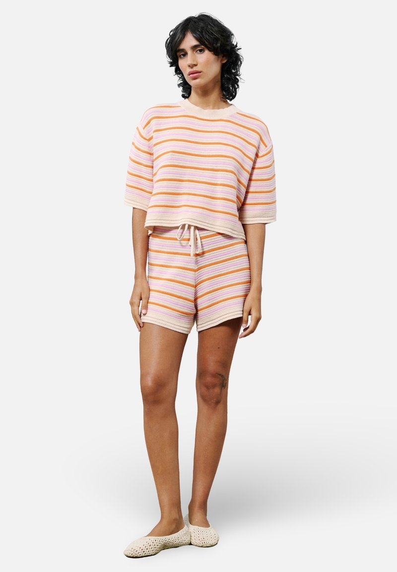 Ensemble de lounge en tricot rayé dans des couleurs pastel, comprenant un haut à manches courtes avec cordon de serrage, un short assorti et un tissu texturé.