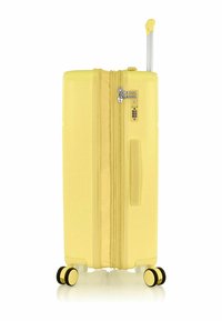 Valigia rigida gialla con manico telescopico, lucchetto a combinazione, due ruote nere e superficie testurizzata per una migliore presa.