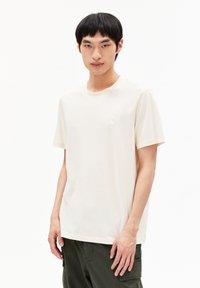 Kurze Ärmeln, cremefarbene Baumwoll-T-Shirt mit einem dezenten gestickten Logo auf der linken Brust, in lässiger Passform und klassischem Rundhalsausschnitt.