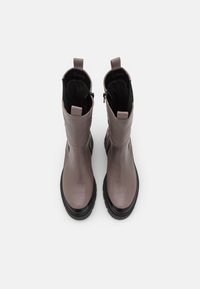 Botas de tobillo de cuero marrón con un acabado suave, suela de goma negra y lengüetas de tiro. Presentan un cierre lateral con cremallera y un forro interior texturizado.