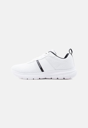 White athletic sneaker with breathable mesh material, black inner lining, pull tab, and "Jack & Jones" branding on side stripe.