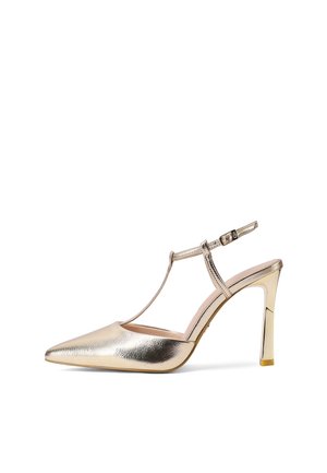 Escarpin doré à bout pointu avec bride en T et boucle à la cheville sur fond blanc.