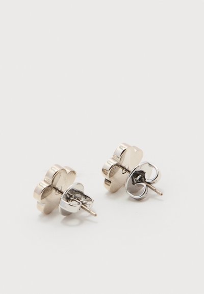 Ζευγάρι ασημένια σκουλαρίκια καρφάκια σε σχήμα λουλουδιού με κλείσιμο πεταλούδας επάνω σε λευκή επιφάνεια.