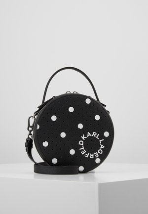 Sac à main rond noir à pois blancs avec texte blanc circulaire "KARL LAGERFELD,", doté d'une poignée supérieure et d'une bandoulière détachable.