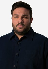 Tummansininen nappipaita, jossa on kaulus ja tasku vasemmassa rinnassa. Valmistettu teksturoidusta kankaasta, sopii arkikäyttöön.
