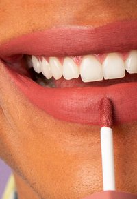 Matte flytande läppstift i en varm, rosig nyans applicerat på släta, något fylligare läppar, med en skumapplikator för exakt applicering.