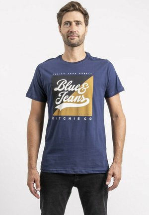 T-shirt en coton bleu marine avec un graphique carré portant l'inscription "Blue & Jeans" en écriture blanche sur un fond jaune. Manches courtes et col rond.