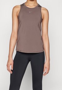 Débardeur de sport sans manches marron avec un col rond et un petit logo Nike en gris, fabriqué à partir d'un tissu lisse et léger.