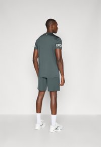 Męska odzież sportowa w ciemnoszarym kolorze, z okrągłym dekoltem, krótkimi rękawami i szortami, z napisem "BORG" na lewym rękawie.