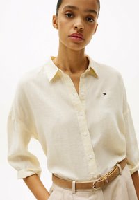 Beige, lichtgewicht knoopshirt met een kraag en opgerolde mouwen, met subtiele strepen en een klein geborduurd logo op de borst.