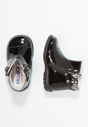 Botines de cuero negro charol con detalles plateados, cierre lateral con cremallera y suela de goma texturizada. Interior con espuma viscoelástica.