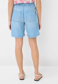 Shorts in denim azzurro chiaro con vita elasticizzata, orli rollati e due tasche posteriori. Il materiale sembra morbido con una texture liscia.