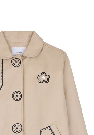 Μπεζ μπουφάν Marc Jacobs με στρογγυλεμένο γιακά, μεγάλα μαύρα κουμπιά με μαύρο περίγραμμα και μαύρο λουλουδένιο σχέδιο στο πάνω μέρος του στήθους.
