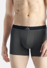 Dunkelgraue Herrenboxershorts mit einem schwarzen Bund, der ein dezentes Logo trägt. Das Material wirkt dehnbar und hat eine glatte Textur.