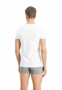 Weißes kurzärmeliges T-Shirt mit Rundhalsausschnitt, von hinten gezeigt, kombiniert mit grauen Boxershorts. Der Stoff sieht glatt und leicht aus.