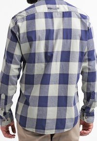 Retro della camicia a quadri in blu navy e grigio chiaro. Realizzata in tessuto con bottoni ai polsini e orlo curvo. Senza loghi visibili.