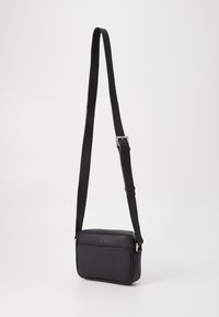 Borsa a tracolla nera in pelle con texture liscia, forma rettangolare, cinturino regolabile e chiusura lampo argentata.