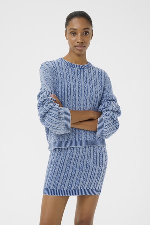 Strick 2-teiliger Satz in verschiedenen Blautönen. Der Pullover hat ein Zopfmuster mit gerippten Bündchen. Der Minirock passt zum Muster des Tops.