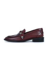 Mocasines de cuero burdeos con punta afilada y hebilla de metal decorativa. Presentan un bajo tacón negro y una textura suave y pulida.