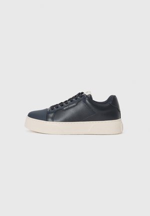 Navy leather sneaker with a textured finish, contrasting white rubber sole, round toe, and flat laces, featuring subtle branding on the side.