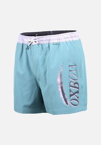 Short de bain bleu clair avec ceinture élastique blanche et cordon, avec le logo "OXBOW" en grandes lettres sur la jambe droite.