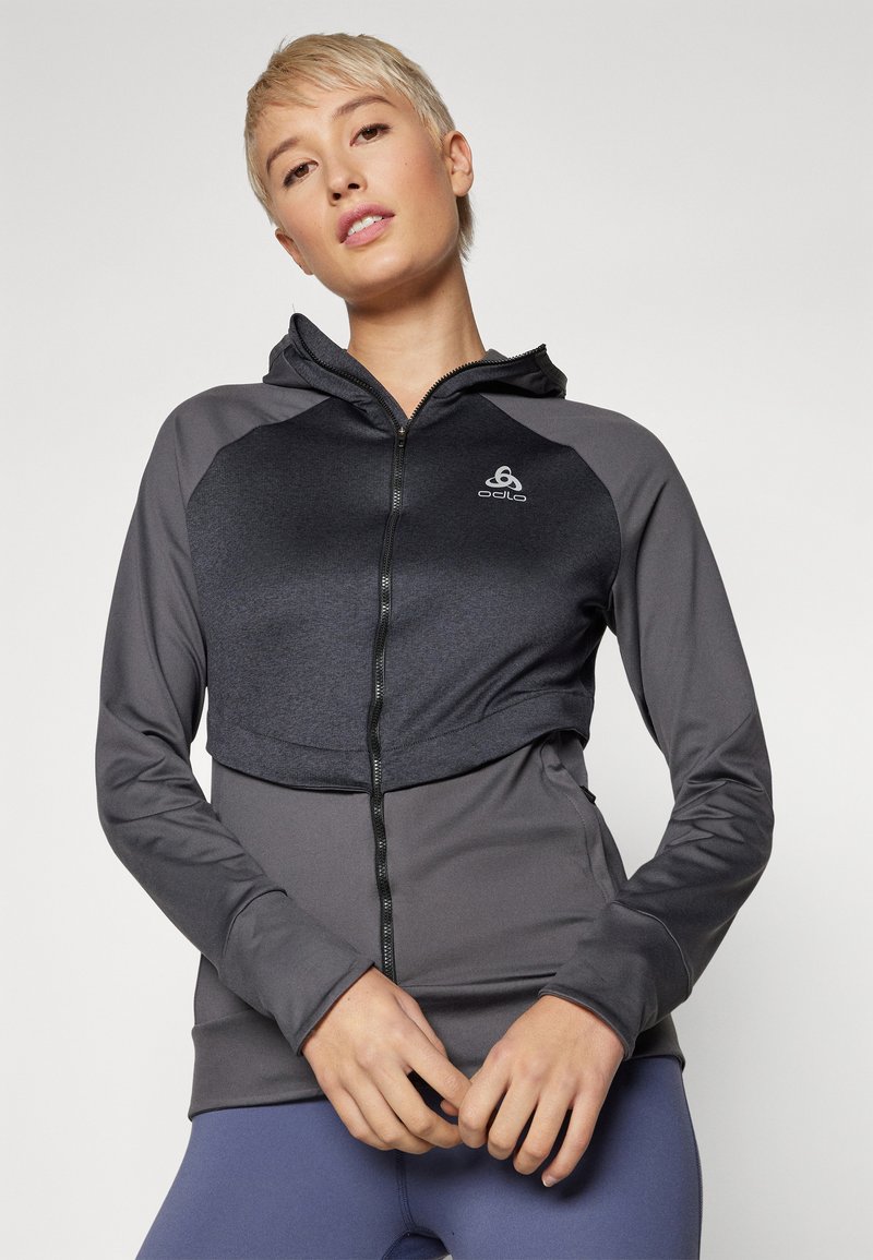 Kapuzensweatjacke mit einem strukturierten grauen Oberteil und glattem dunkelgrauen Unterteil. Verfügt über ein Logo auf der Brust und eng anliegende Ärmel.