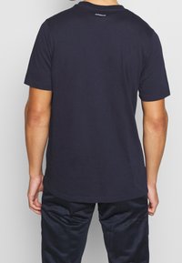 Camiseta de algodón color azul marino de manga corta, con cuello redondo y un dobladillo ligeramente curvado; presenta el logo "AEROREADY" en la parte posterior del cuello.