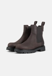 Ruske nahkalenkki Chelsea-saappaat mustilla elastisilla sivupaneeleilla, vetotapeilla ja karkeilla mustilla kumipohjilla. Suuntaa-antava rakenne ja minimalistinen muotoilu.