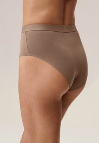 Beżowe bawełniane figi z wysokim stanem, gładką fakturą i przeszyciami. Charakteryzują się bezszwową konstrukcją i jednolitym kolorem.