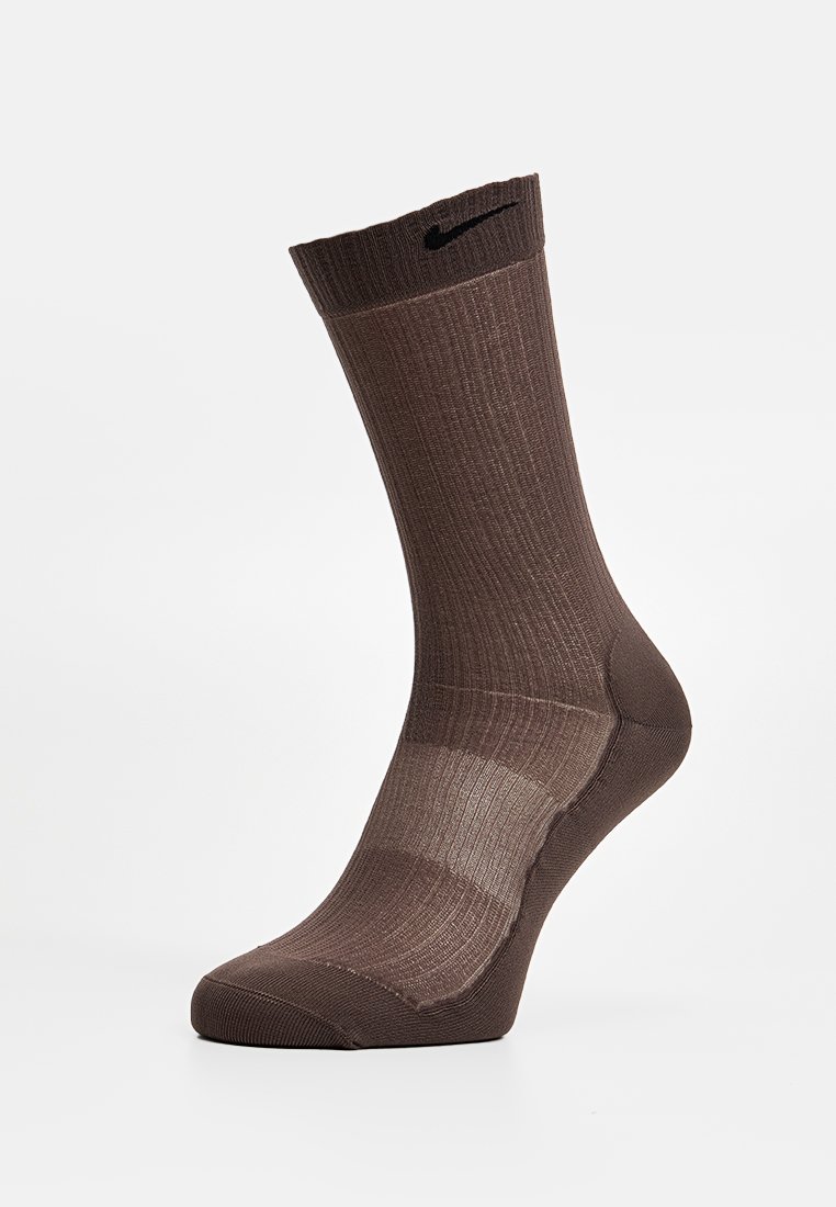 Braune SportSocke mit gerippter Struktur, verstärktem Zehen- und Fersenbereich sowie einem kleinen schwarzen Logo an der Oberseite. Design in mittlerer Wadenlänge.