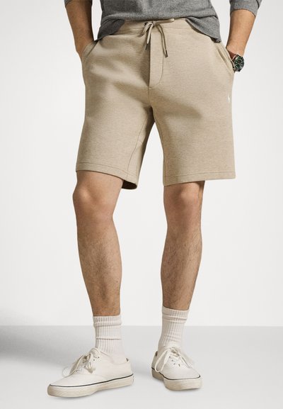 Pantaloncini da ginnastica beige con elastico in vita e coulisse. Tessuto testurizzato, tasche laterali, con un piccolo logo sul davanti.