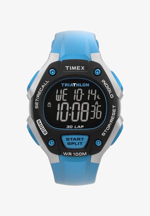 Digitalni Timex Triathlon sat s plavim remenom, prikazuje vrijeme, datum i štopericu za 30 krugova, s vidljivim tipkama za odabir moda i start/split.