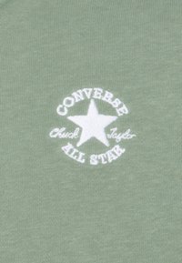 Olive zelené bavlnené tričko s bielou vyšitou nášivkou s hviezdou a textom: "CONVERSE Chuck Taylor ALL STAR."