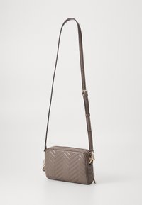 Borsa a tracolla marrone trapuntata con motivo a zigzag, hardware color oro, tracolla regolabile e chiusura con zip. Forma rettangolare compatta.