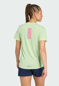 Vaaleanvihreä lyhythihainen t-paita, jossa on kolme vaaleanpunaista pystysuoraa raitaa selässä. Valmistettu pehmeästä kankaasta, yhdistetty tummansinisiin shortsit.