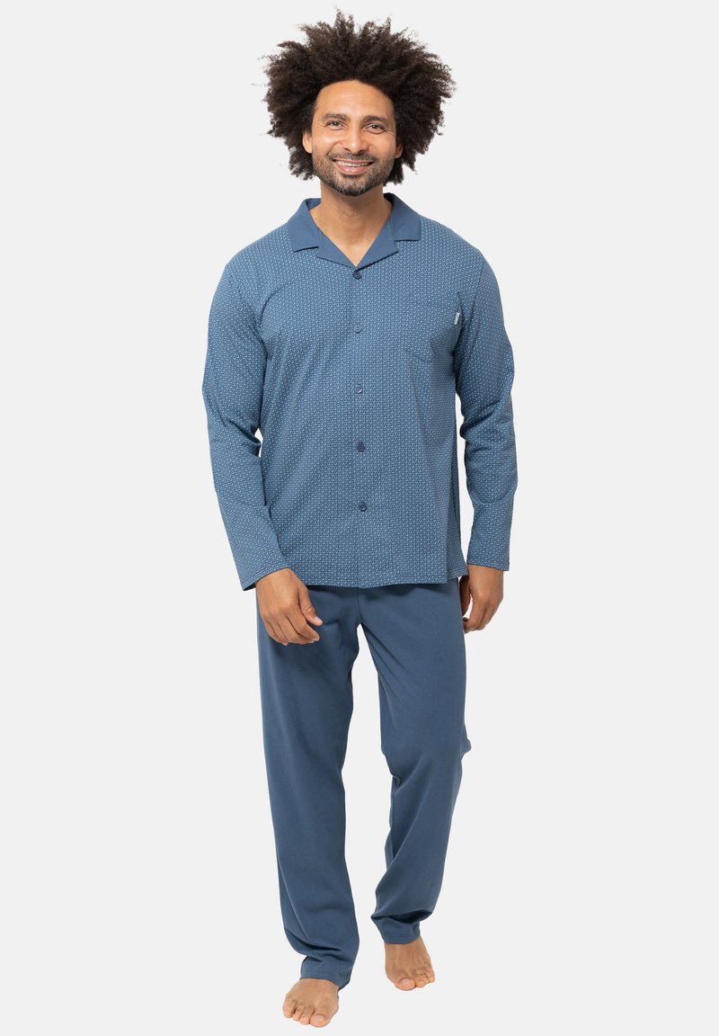 Sinipeläinen kuvioitu yöasu, joka sisältää pitkähihaisen napituspaidan ja siihen sopivat housut. Paita on varustettu rintataskulla ja pehmeällä kangasrakenteella.