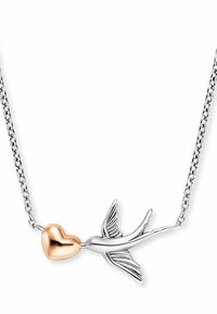Collana d'argento con un uccello stilizzato le cui ali sono decorate con dettagli intricati, che tiene un cuore in oro rosa, su una delicata catena.