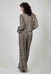 Súprava pohodlného oblečenia s leopardím vzorom vyrobená z hodvábneho materiálu, s voľným a uvoľneným strihom. Košeľa má dlhé rukávy a nohavice majú rovný strih.