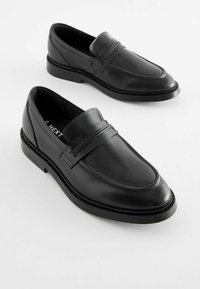 Svarta läderloafers med en slät yta, rund tå och accentband över vampen. Stabil svart gummisul.