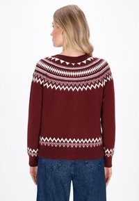 Bordeauxfarbener Strickpullover mit einem weißen geometrischen Yoke-Design, gerippten Bündchen und Saum. Der Stoff hat eine glatte Textur und eine klassische Passform.