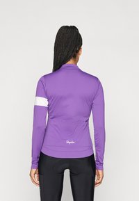 Jersei de ciclismo de manga longa roxo com uma faixa branca no braço, apresentando um corte slim e bolsos traseiros para armazenamento. Tecido macio e elástico.